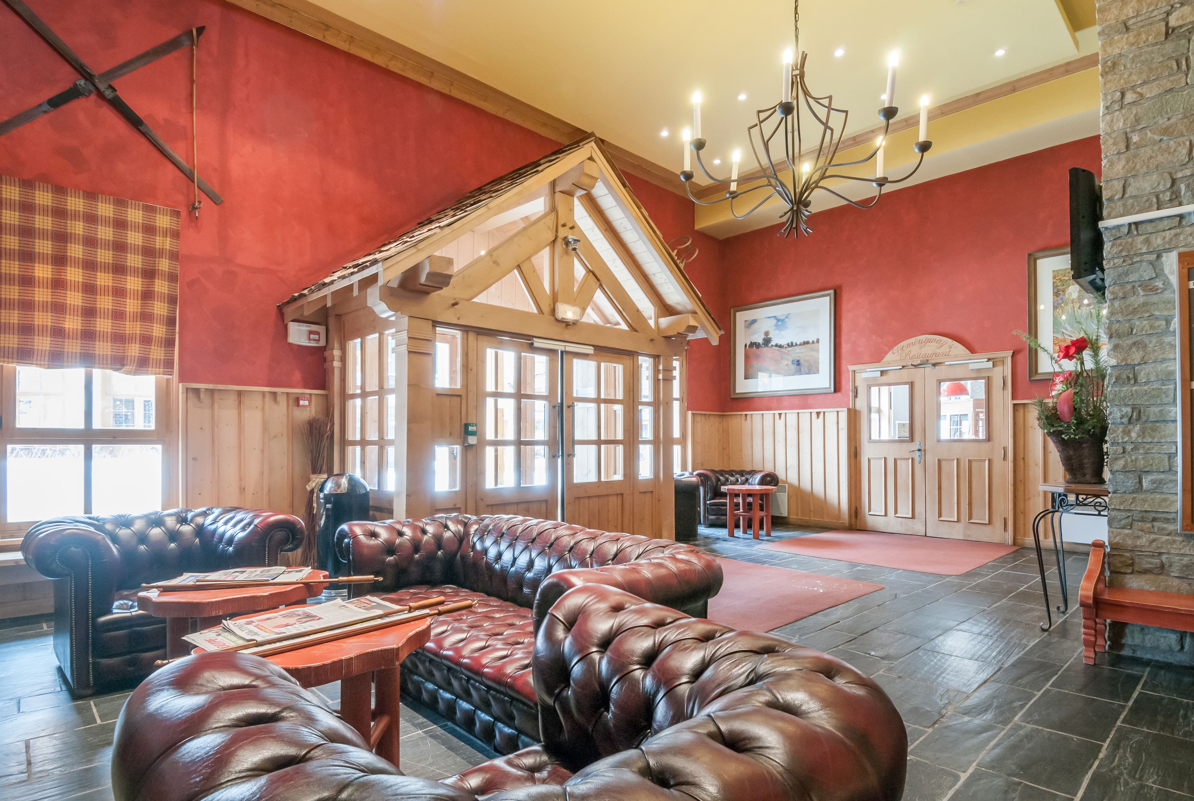 A cozy lobby with a wooden ceiling, leather seating, and a stone accent wall.