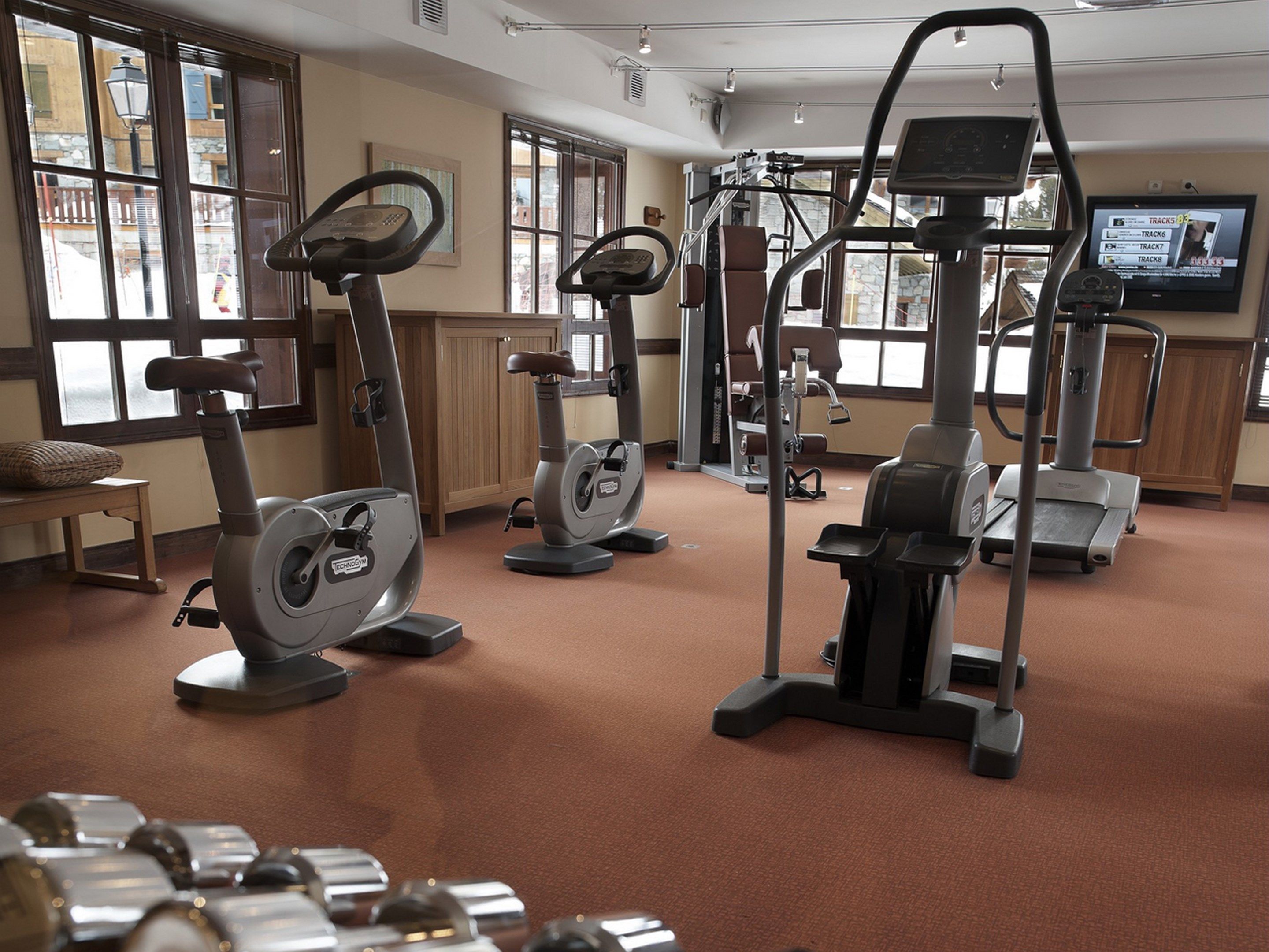 Une salle de sport équipée de vélos d’appartement, de machines elliptiques et d’un tapis de course.