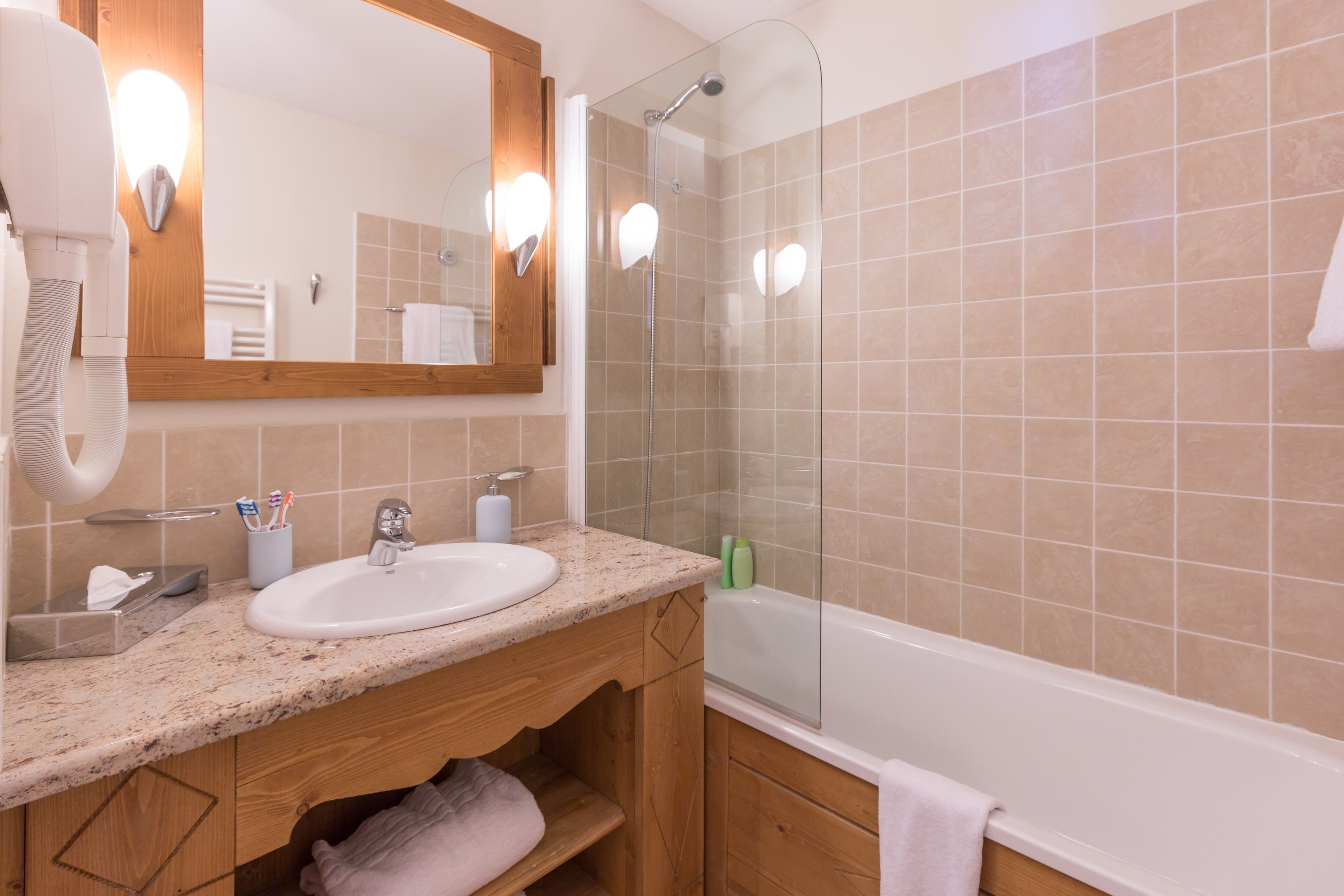 A bathroom with a sink, mirror, towel rack, and shower.