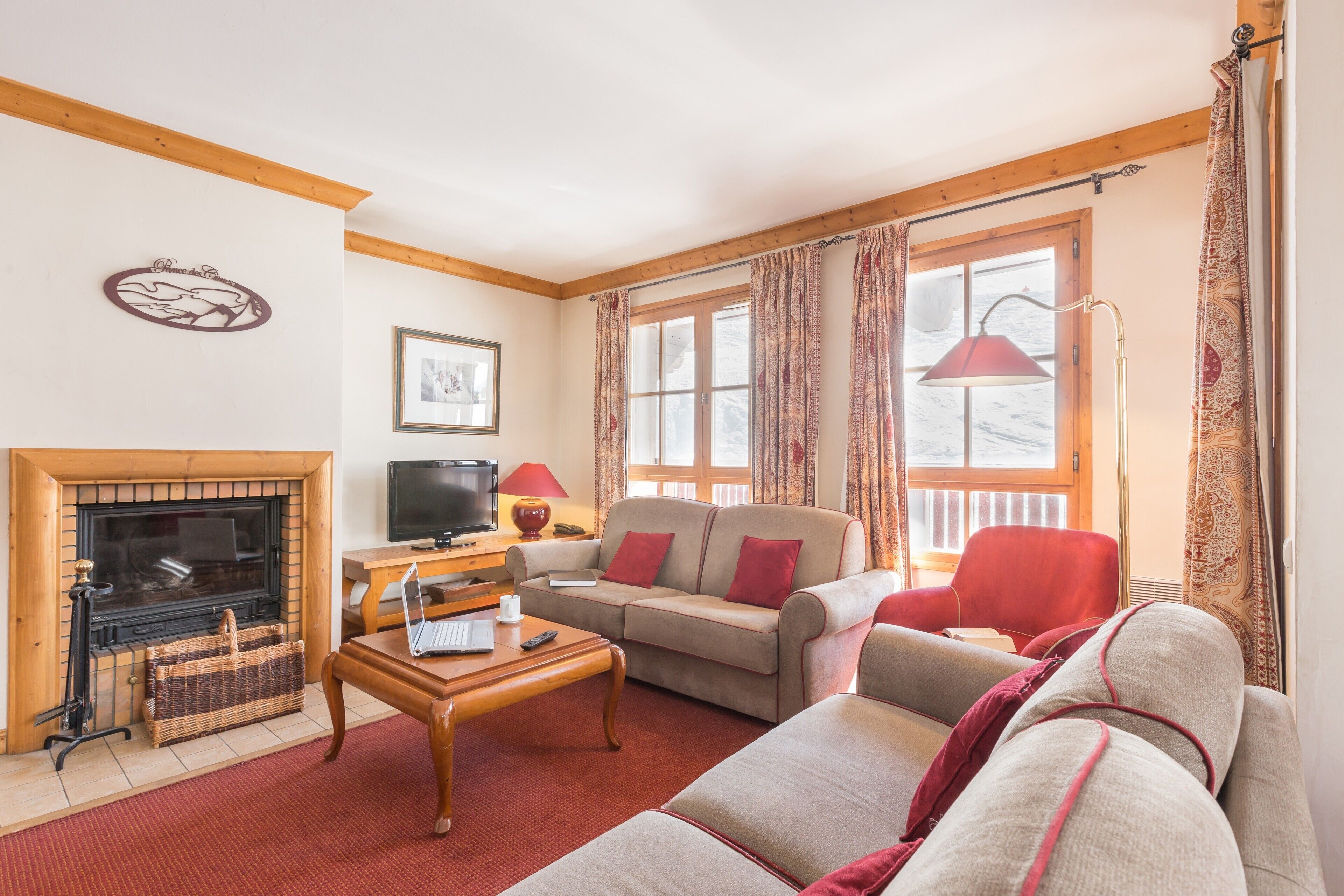 Una sala de estar acogedora con chimenea, un sofá, un sillón rojo y una mesa de centro de madera.