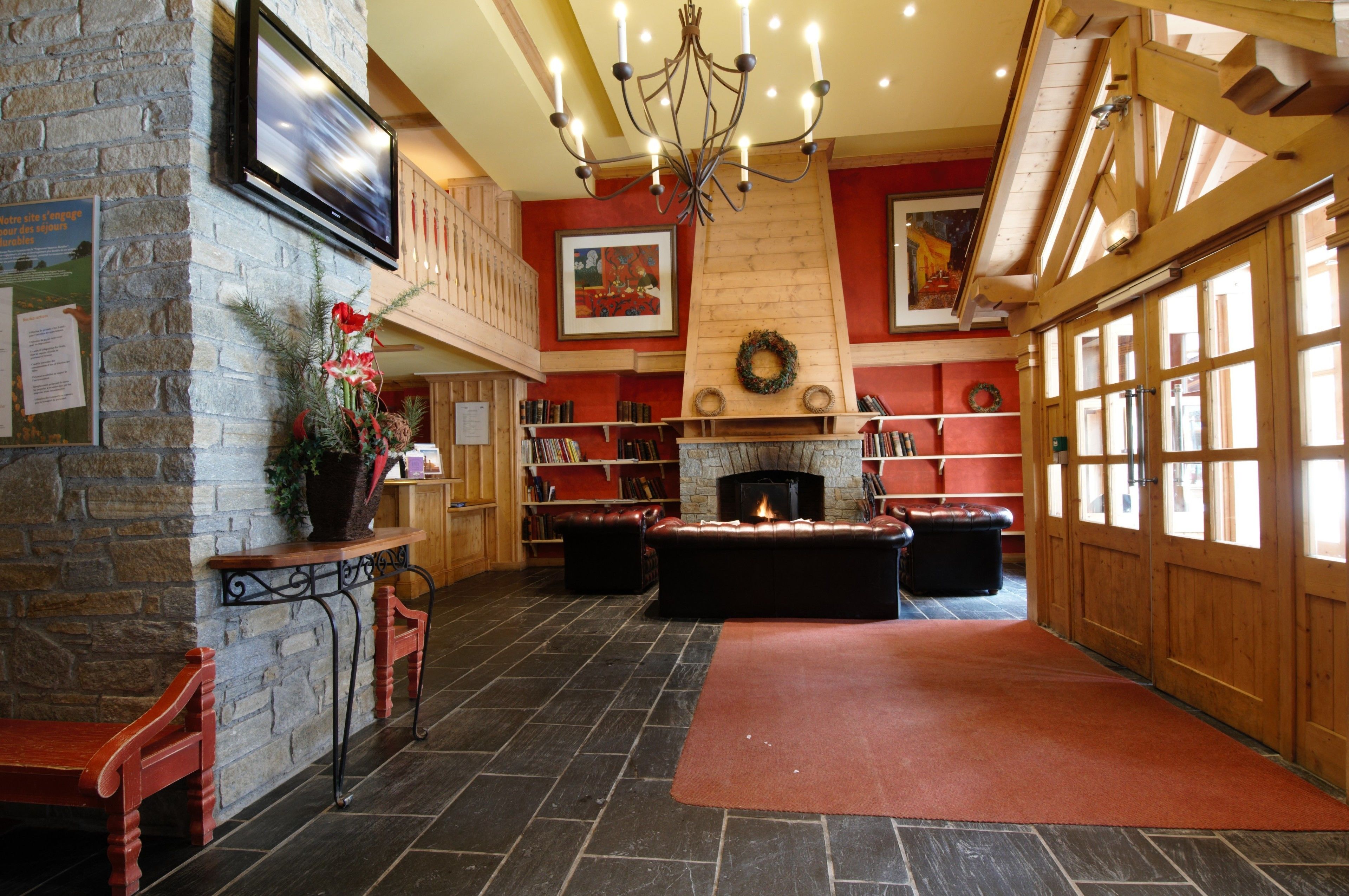 Un hall acogedor con pared de piedra, chimenea, sofá de cuero y escalera de madera.