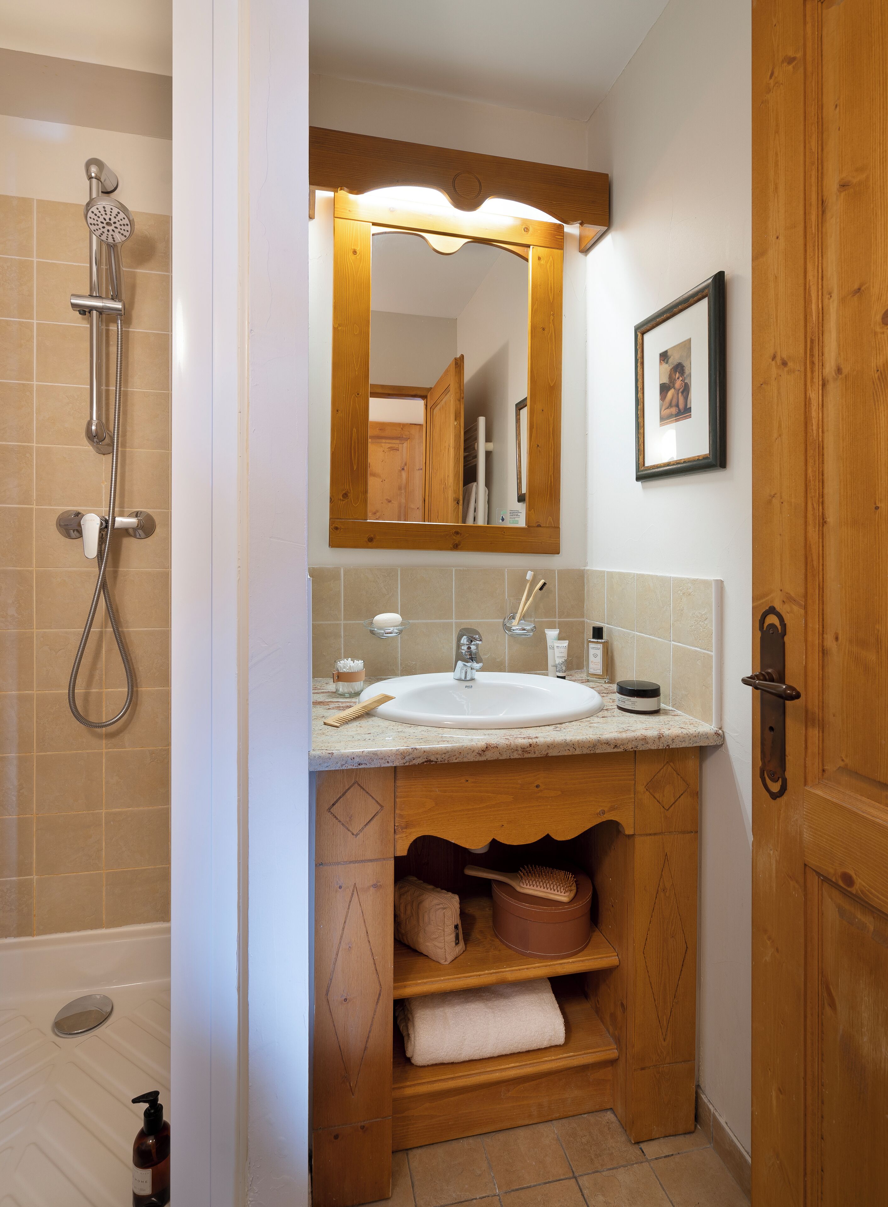 A bathroom with a shower, sink, and wooden vanity.