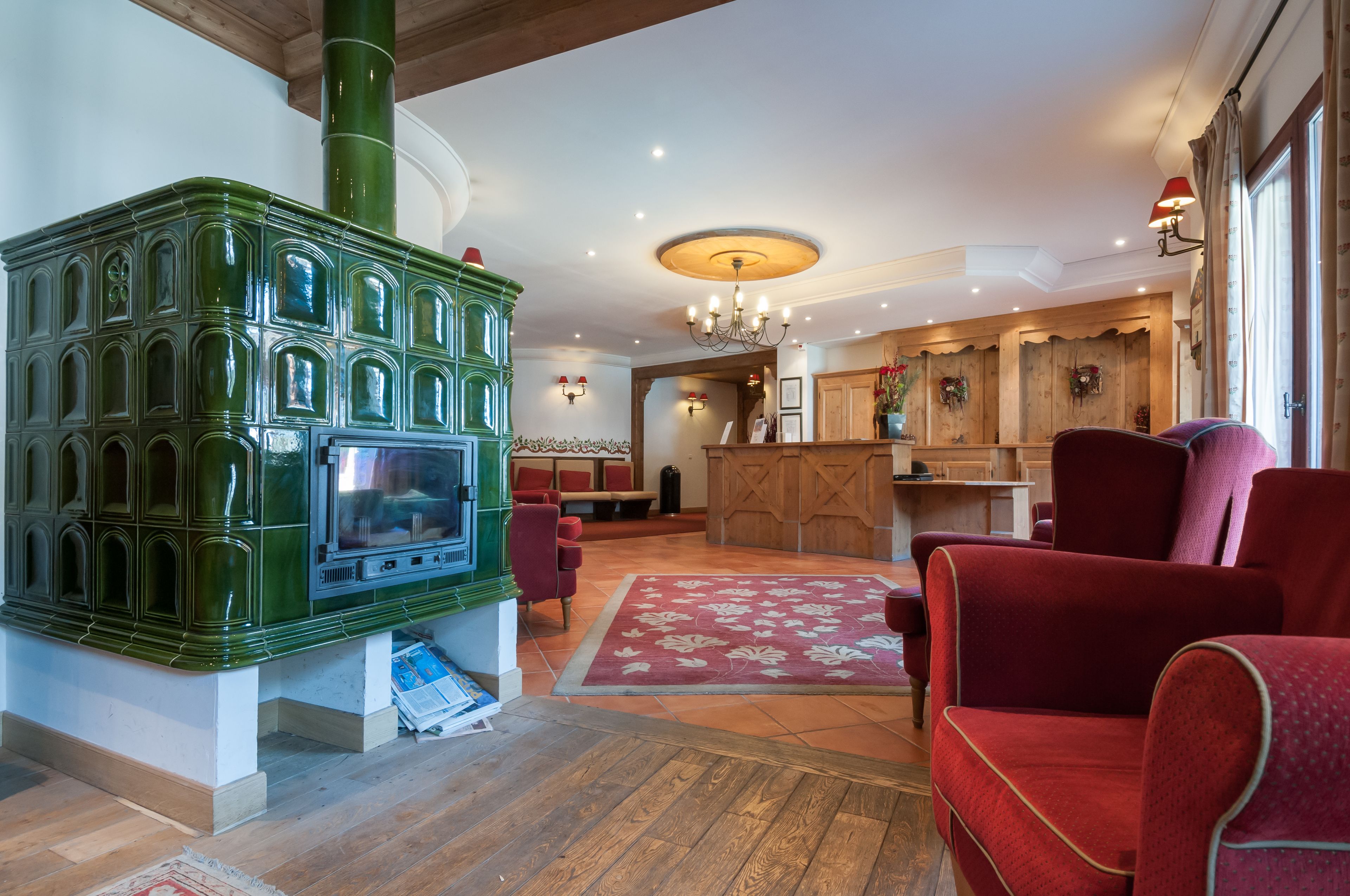 A cozy room with a green wood-burning stove, red upholstered chairs, and a wooden bar area.