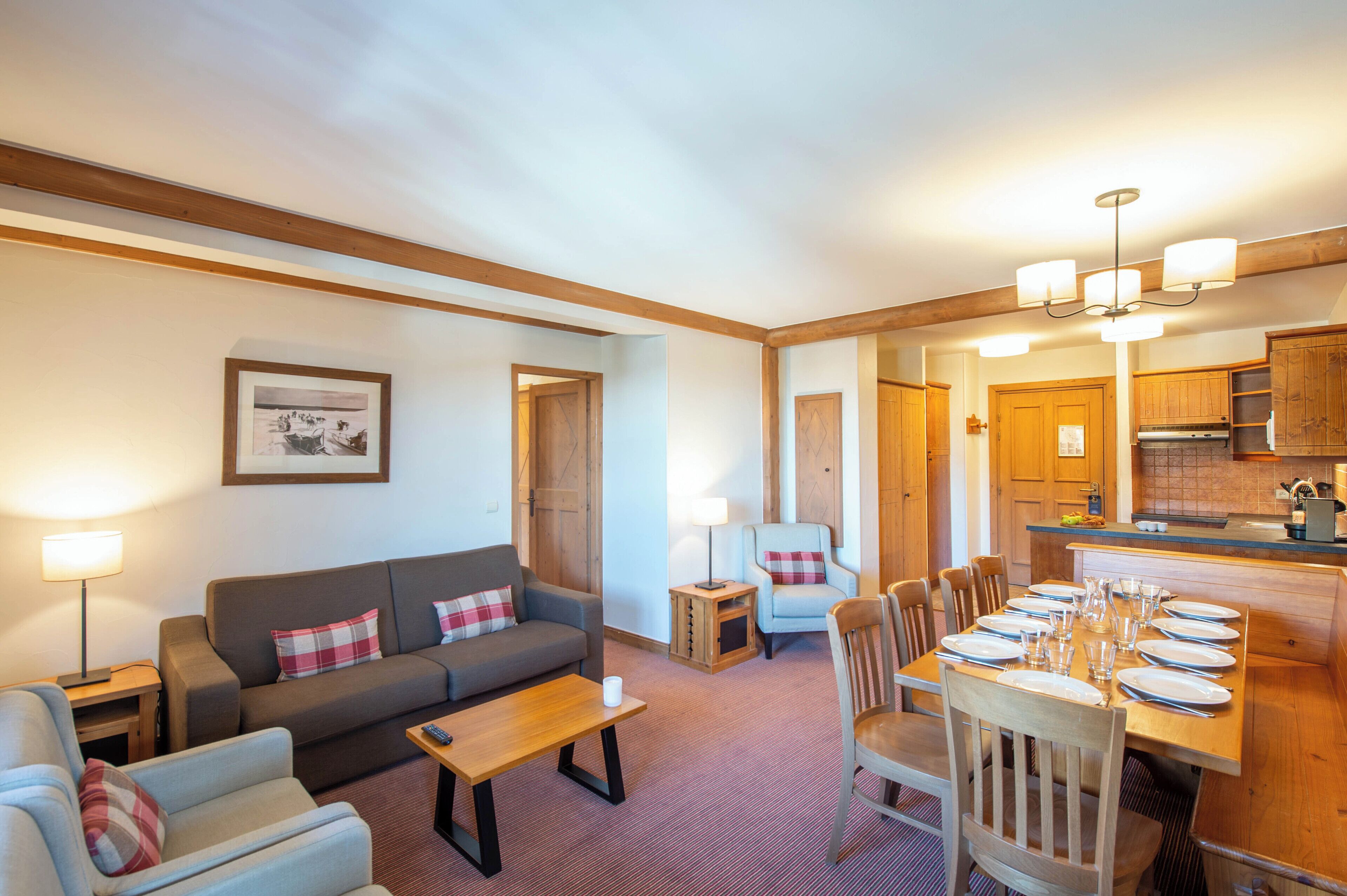 A cozy living room with a sofa, armchairs, a coffee table, and a dining area with chairs and a table set for a meal.