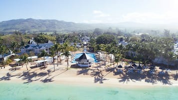 Relax by the large pool surrounded by lounge chairs and umbrellas, overlooking the serene beach and clear waters.