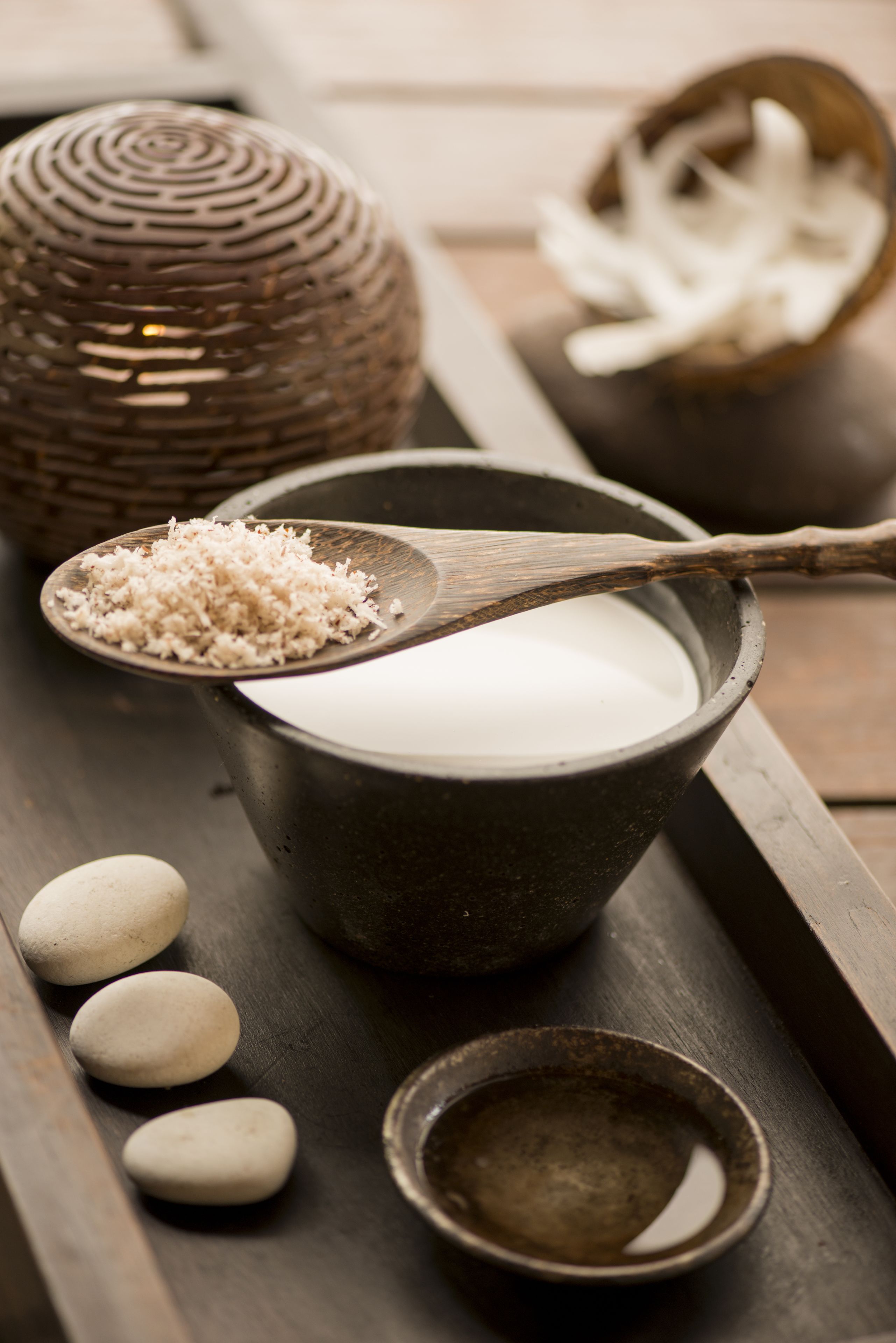 A tray with a bowl of white liquid, a wooden spoon with white granules, and a small bowl with white objects.