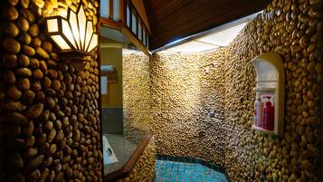 Bathroom features a stone wall design, sink, mirror, and shelf with amenities.