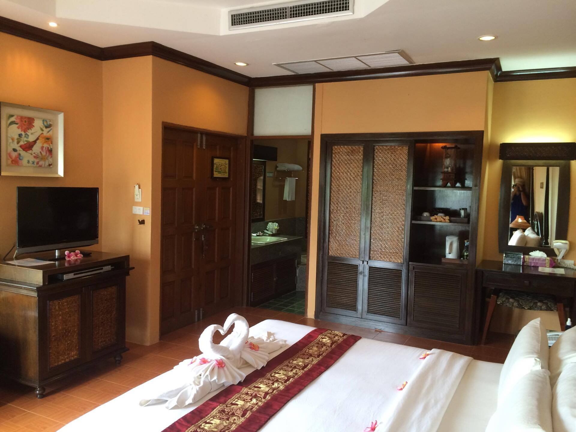 Una habitación de hotel con cama, televisión, armario, baño y espejo.
