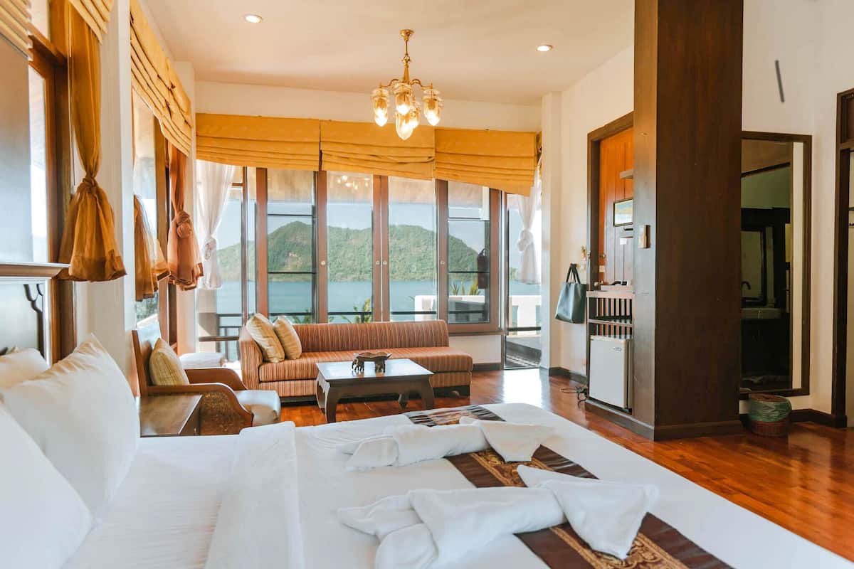 Ruime kamer met een groot bed, een bank, een bijzettafeltje en uitzicht op zee.