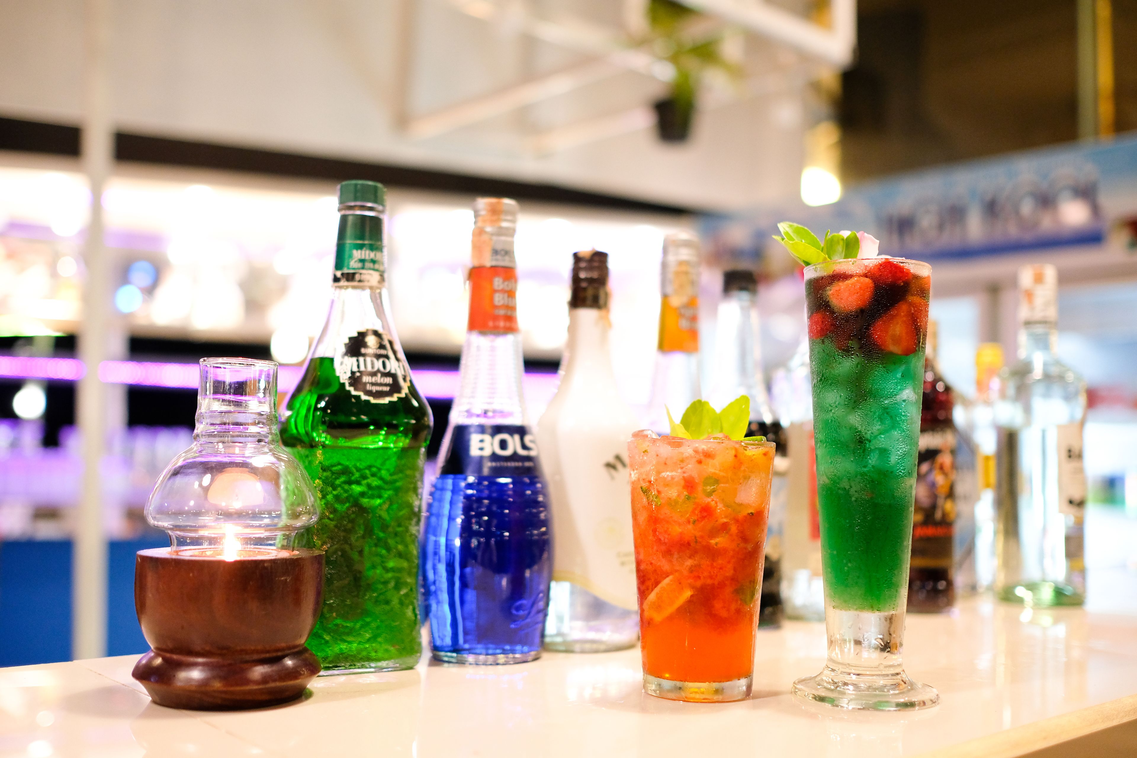 A bar counter with various bottles and glasses of drinks.