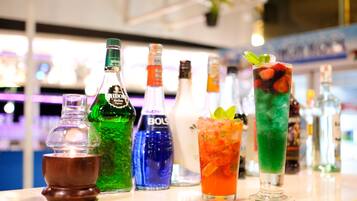 A bar counter with various bottles and glasses of drinks.