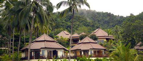 Un resort con varias edificaciones tipo cabaña, rodeado de exuberante follaje y palmeras.