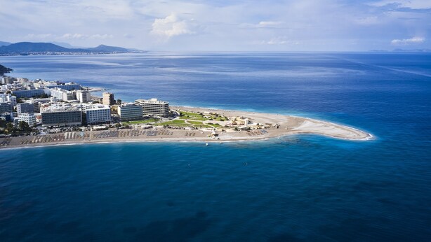 Luftaufnahme einer Küstenstadt mit Strand, Hotels und blauem Meer.