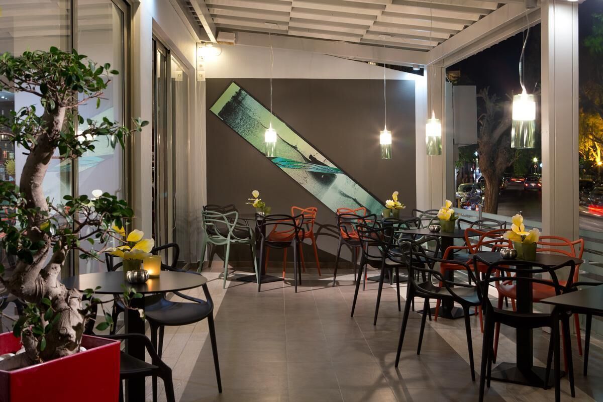 A restaurant with tables and chairs, a large window, and a tree.