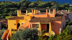 A coastal villa with terracotta roofs, a staircase leading to the upper floor, and a view of the sea.