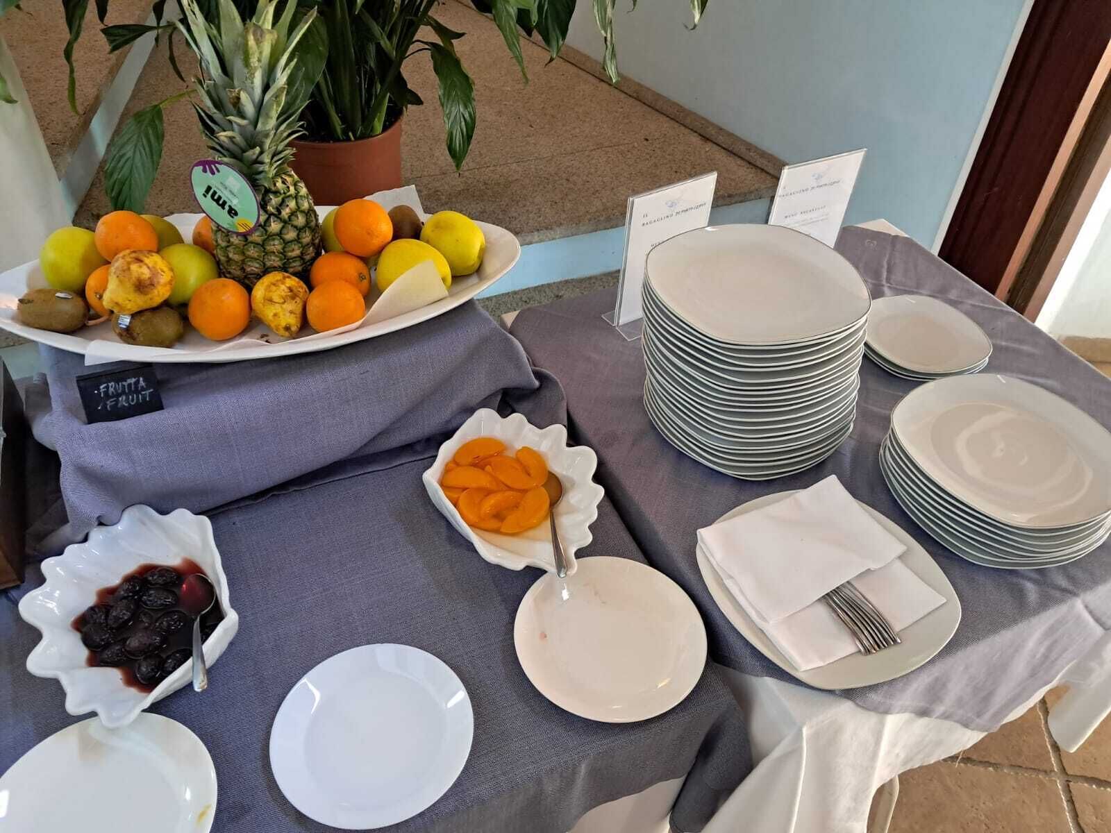 A table set with plates, bowls, and a fruit platter.