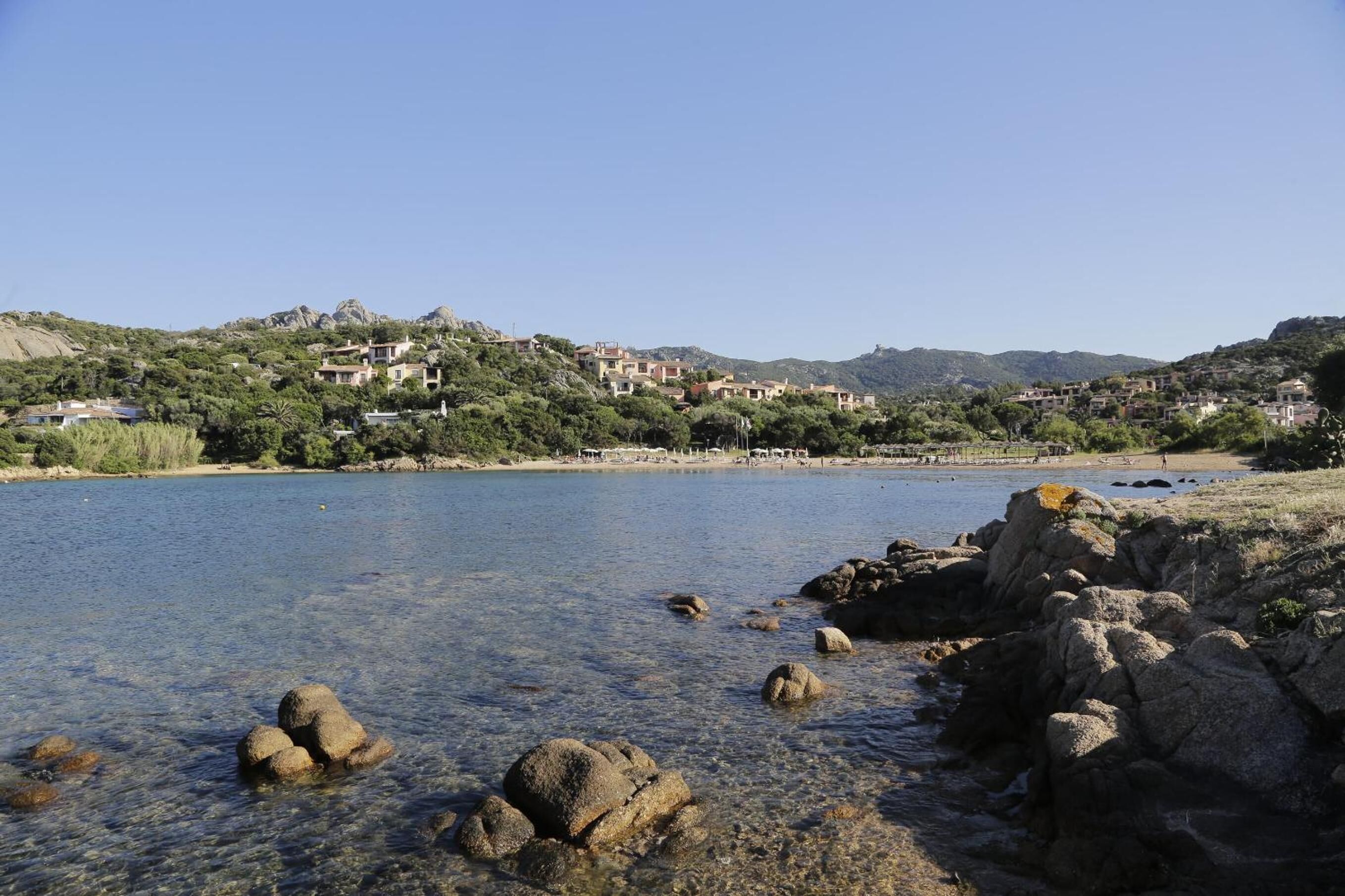 Un pueblo costero con edificios en una ladera con vistas a un lago azul y despejado.