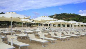 A beach with rows of sun loungers and white umbrellas.