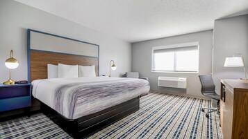 Habitación de hotel con una cama grande, lámparas de noche, un escritorio con silla, una ventana y un radiador.