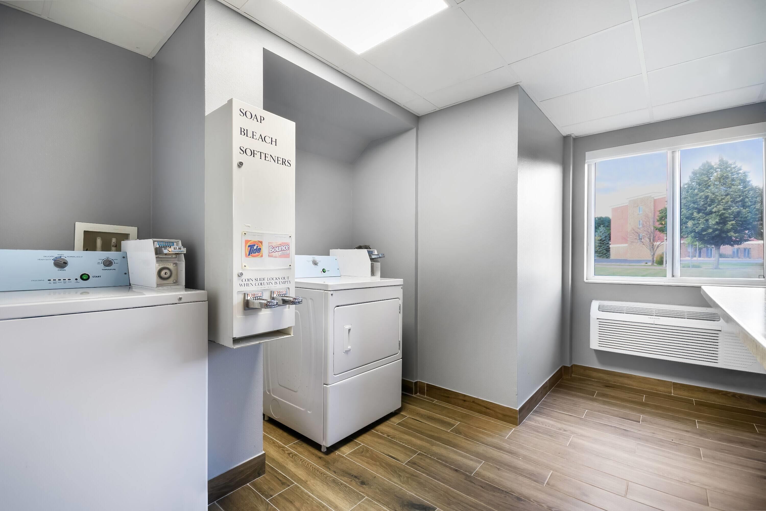 A laundry facility with a washing machine, dryer, and coin-operated machines.