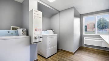 A laundry facility with a washing machine, dryer, and coin-operated machines.