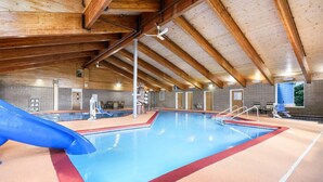 Ein Innenpool mit blauer Rutsche, Holzbalken und gefliesten Wänden.