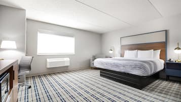 Habitación de hotel con cama, escritorio, silla y un ventanal grande.