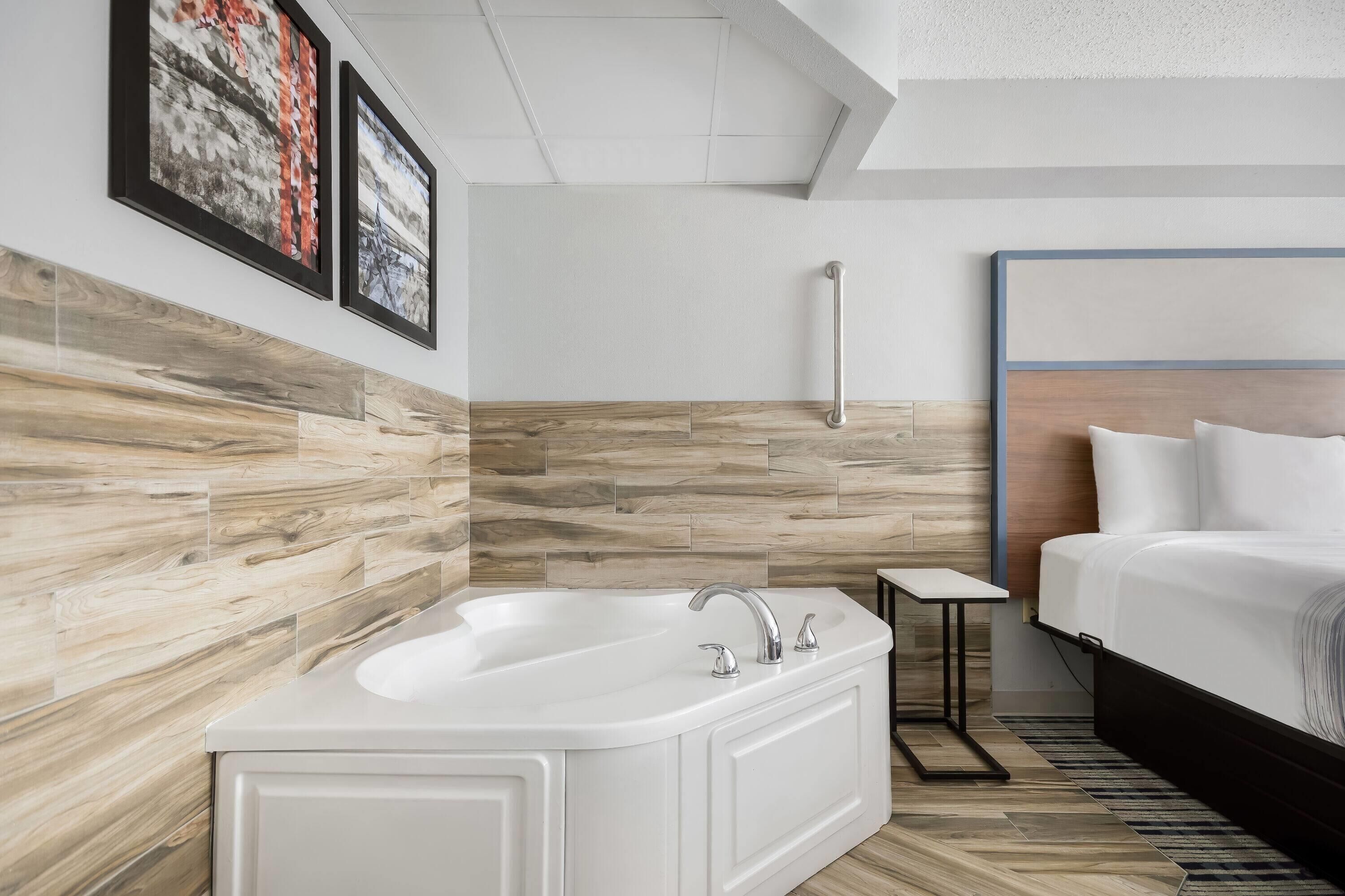 Un baño moderno con una bañera independiente, una mesita de noche pequeña y un cabecero con panel de madera.