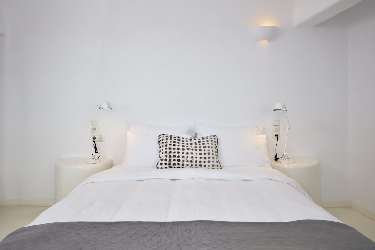 A minimalist bedroom with a bed centered between two bedside tables, each with a lamp.