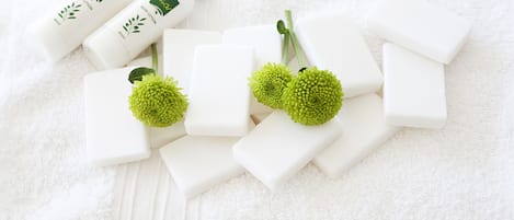 White bath products and green flowers on a white towel.