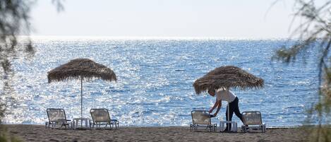 Una playa con tumbonas y una persona organizándolas.