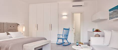 Un dormitorio moderno y minimalista con una cama, una mecedora, una mesita y un sofá.
