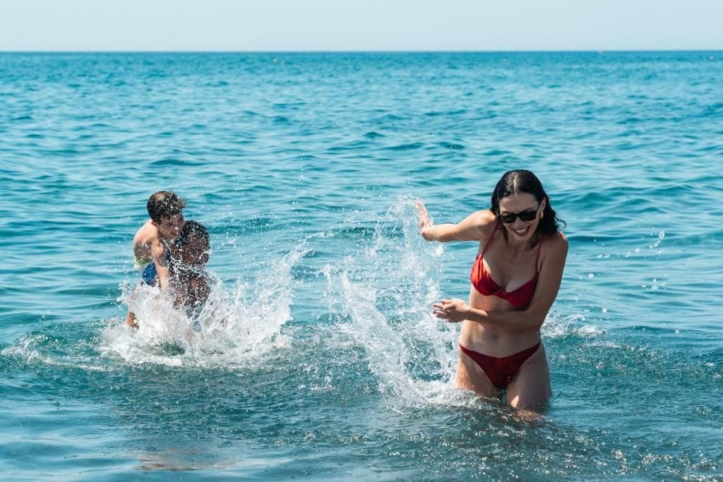 A woman in a red bikini and a man in a blue swimsuit in the ocean.
