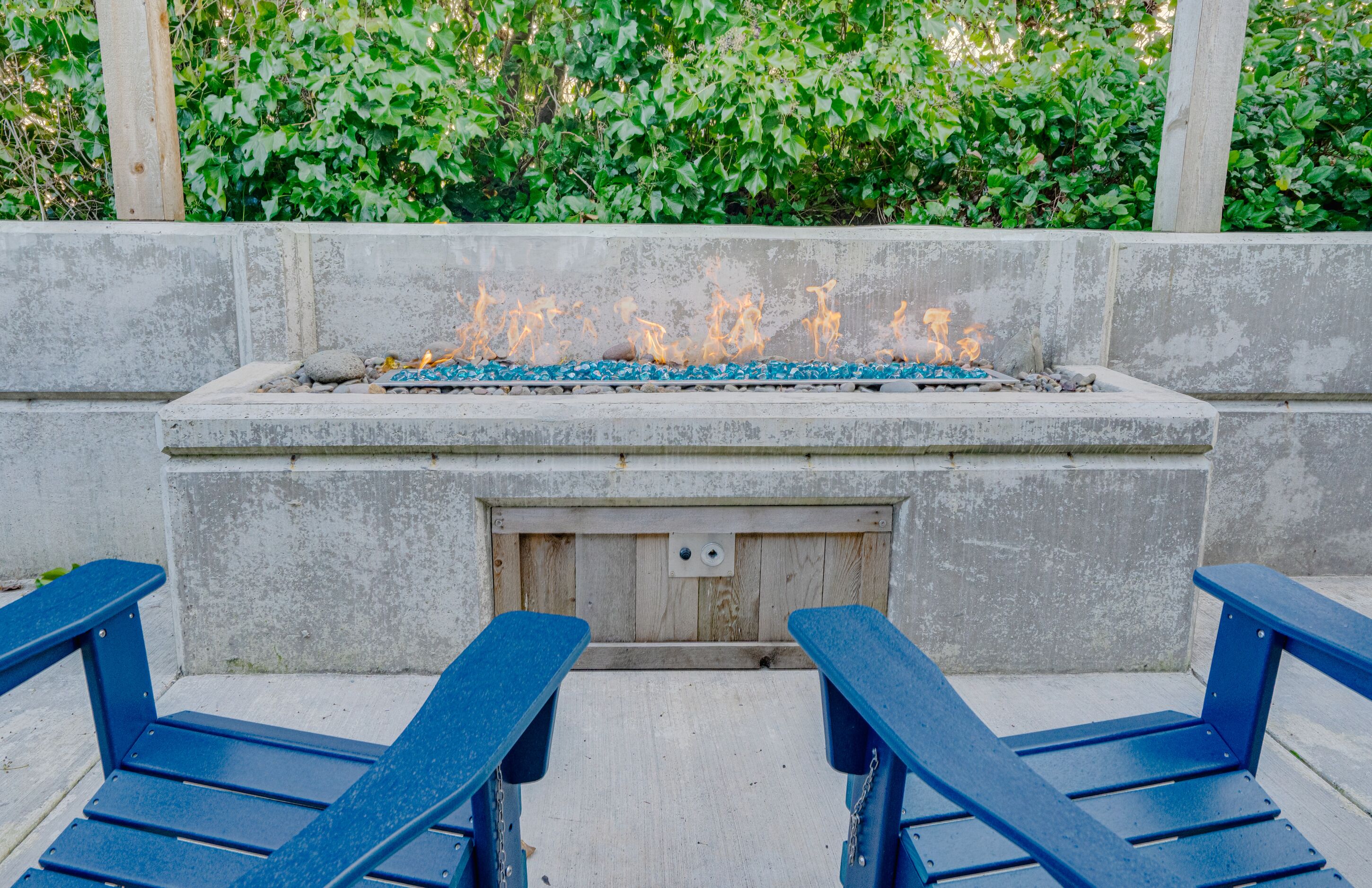 A concrete fire pit with a metal grate, surrounded by a low stone wall.