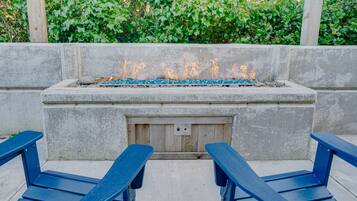A concrete fire pit with a metal grate, surrounded by a low stone wall.