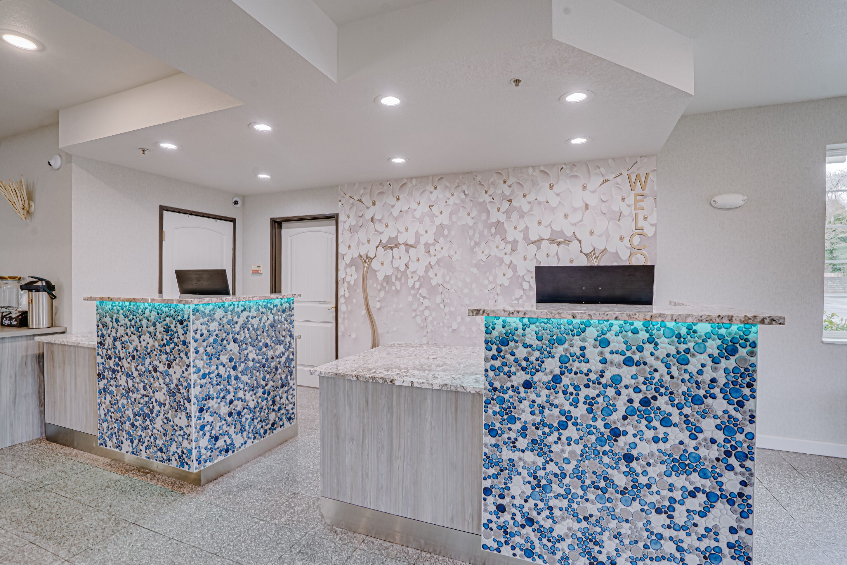 A reception area with two counters, a wall with a floral pattern, and a door in the background.