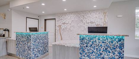 A reception area with two counters, a wall with a floral pattern, and a door in the background.