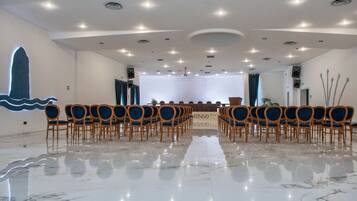 A conference room with rows of chairs, a podium, and a marble floor.