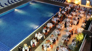 Un espace de restauration aménagé au bord de la piscine, avec des tables et des chaises, une piscine et une vue sur la mer.