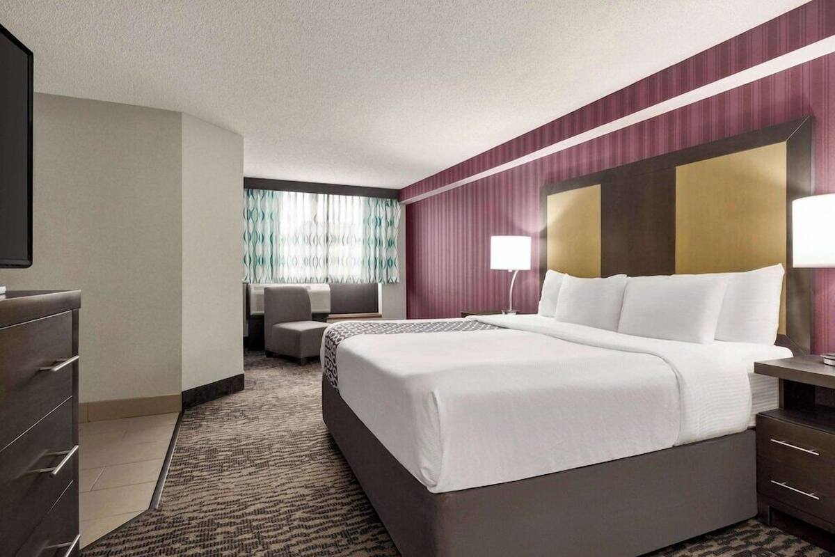 Une chambre d’hôtel avec un grand lit, un bureau, une chaise et un téléviseur.