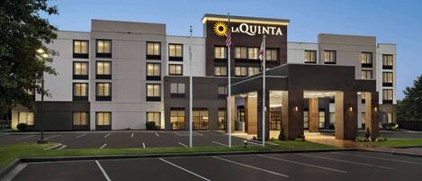 A La Quinta hotel with a modern design, featuring a large parking lot and a well-lit entrance.