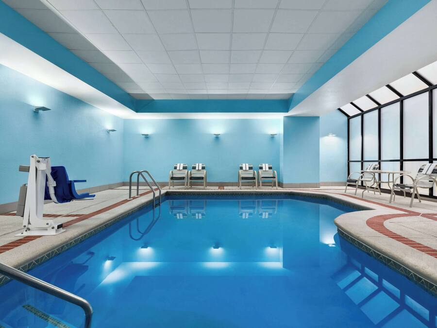 Een zwembad met een blauw interieur, omringd door ligbedden en een kleedruimte.