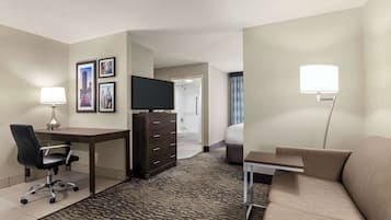 Una habitación de hotel con escritorio, silla, cómoda, cama y televisor.