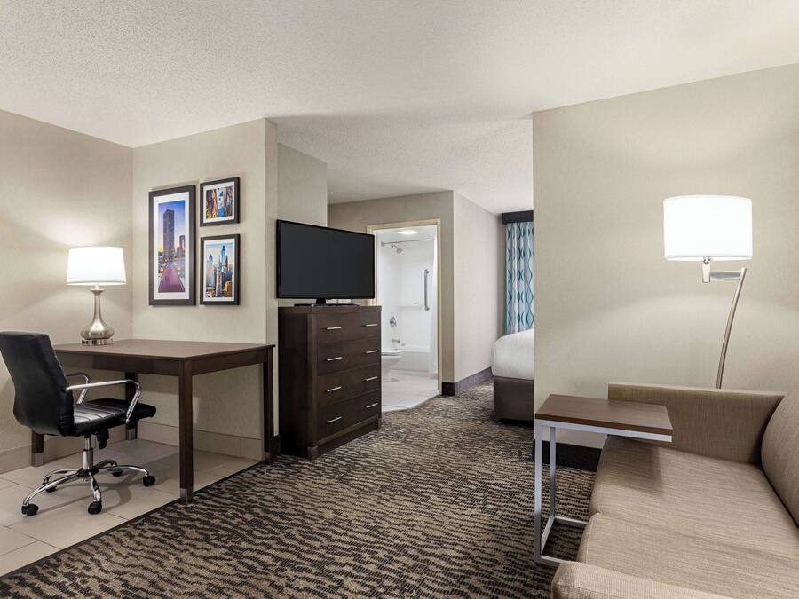 Una habitación de hotel con escritorio, silla, cómoda, cama y televisor.
