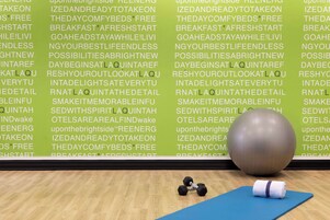 A gym with exercise equipment, a yoga mat, and motivational text on the wall.