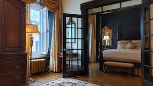 Un dormitorio tradicional con cama con dosel, un espejo grande y un aparador de madera.
