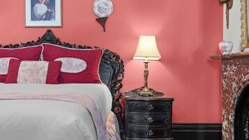 A bedroom with a bed, a dresser, a lamp, a framed picture, and a wall-mounted plate.