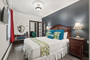 Un dormitorio con cama, mesita de noche, cómoda, espejo y televisor.