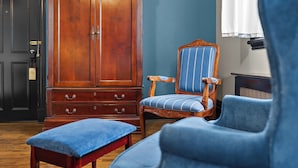 A room with a wooden wardrobe, a blue upholstered chair, and a matching bench. - Hôtel Le Clos Saint-Louis - Par Aneyro (Québec City)