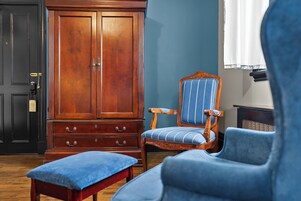 Una habitación con un armario de madera, un sillón tapizado en azul y un banco a juego.